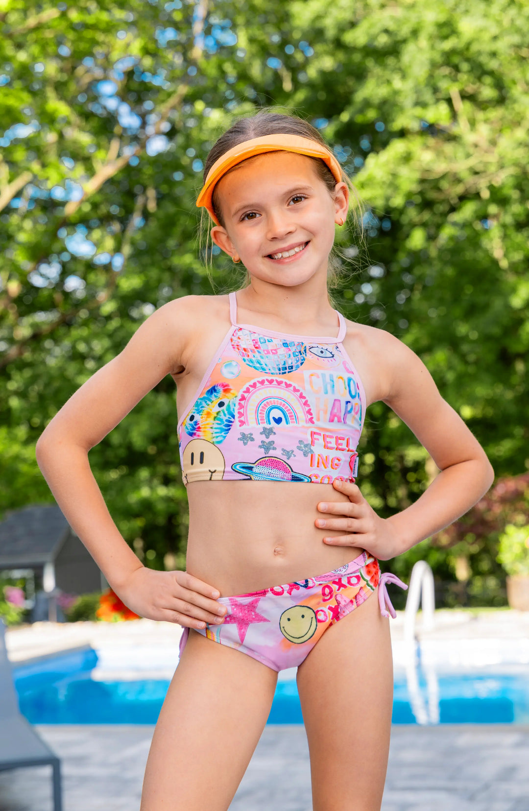 Girl in a colorful printed bikini swimsuit standing by a pool, ready for swimsuit care tips