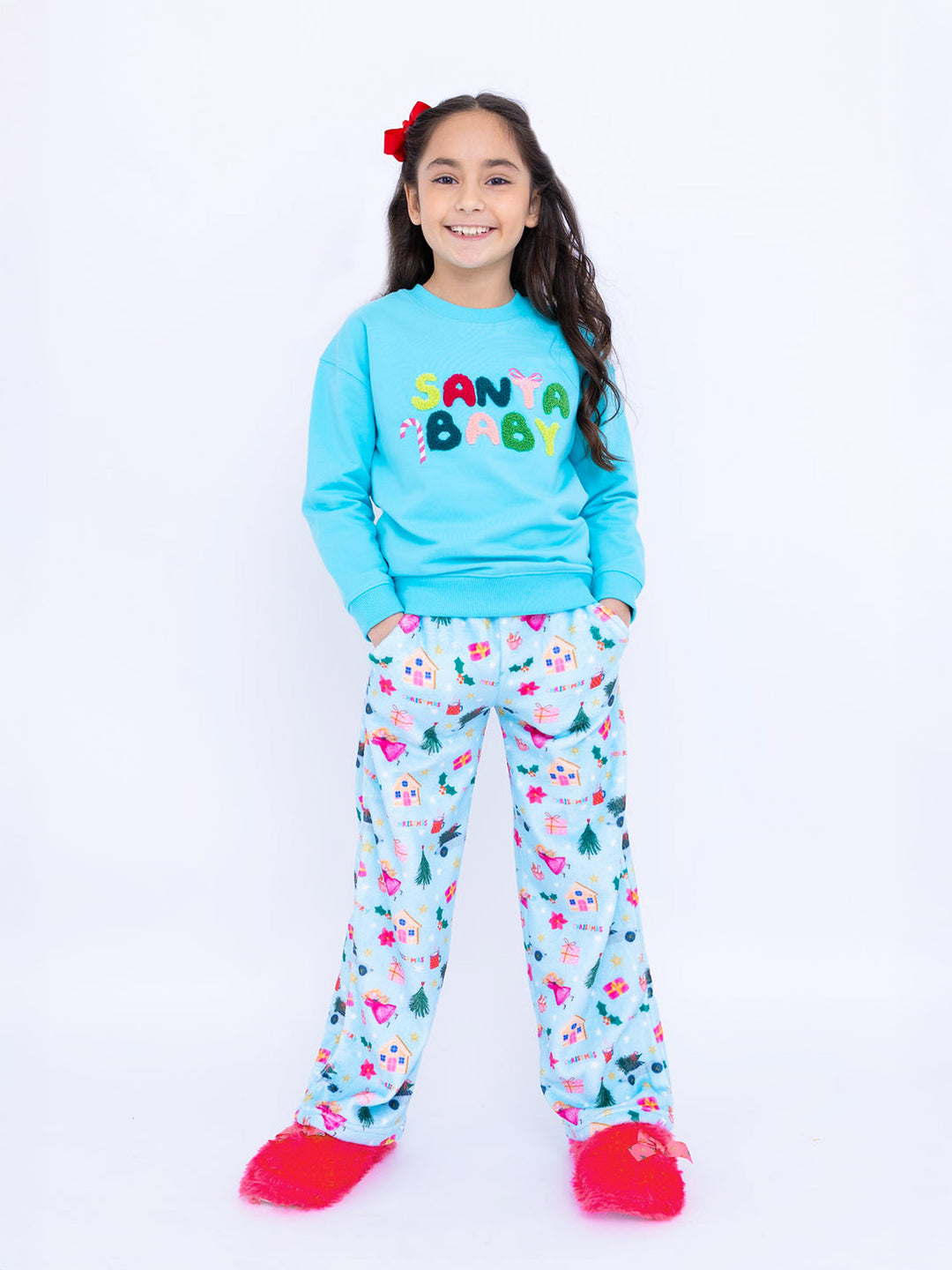 Girl wearing a blue 'Santa Baby' sweatshirt and plush pant with colorful patterns on a white background