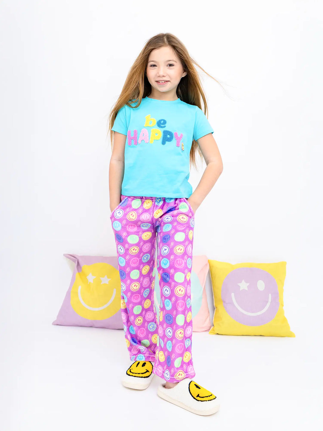Young girl wearing a 'Be Happy' t-shirt and plush lounge pants with smiley face print