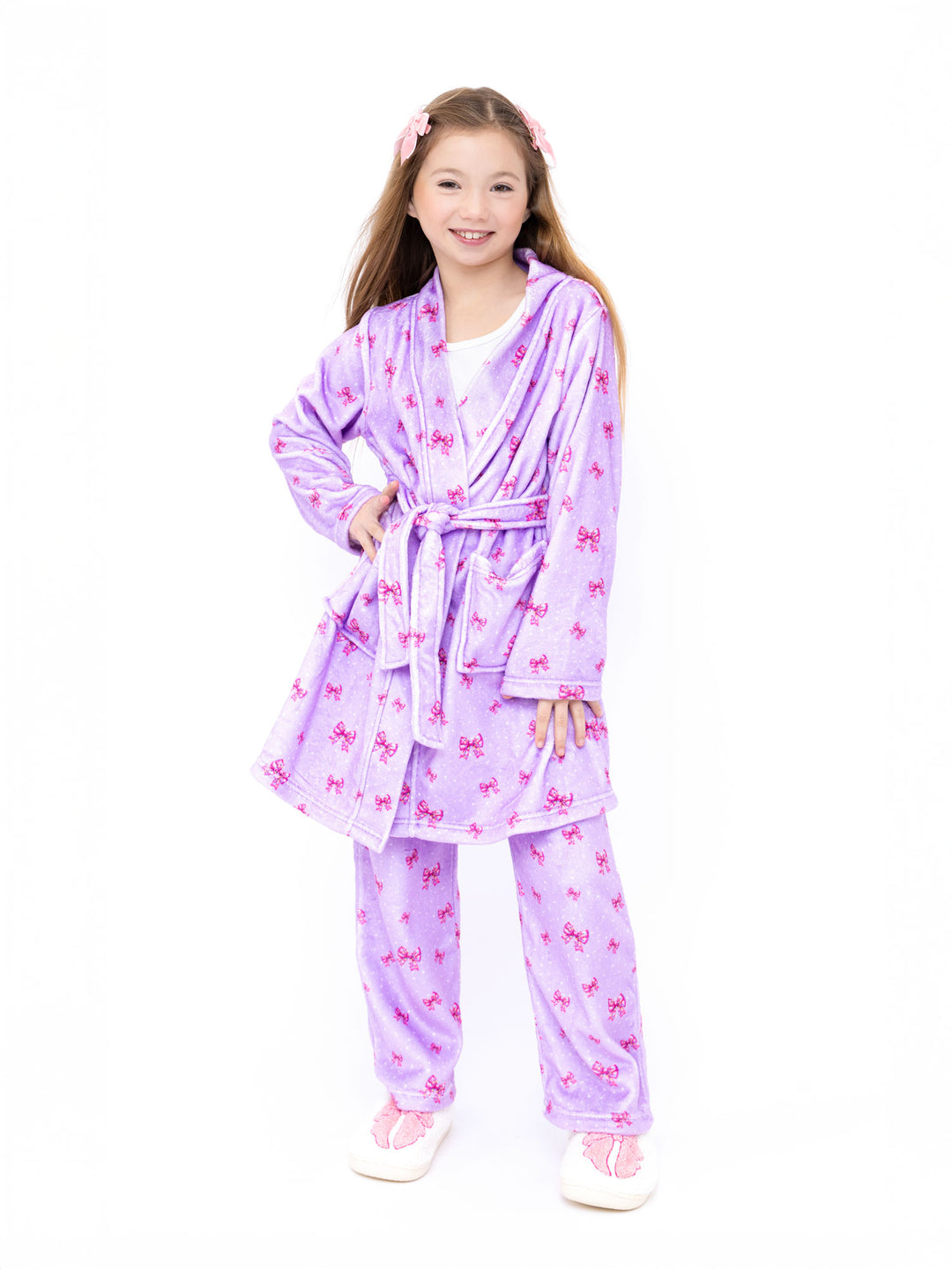 Young girl wearing a purple robe with pink bow patterns on a white background