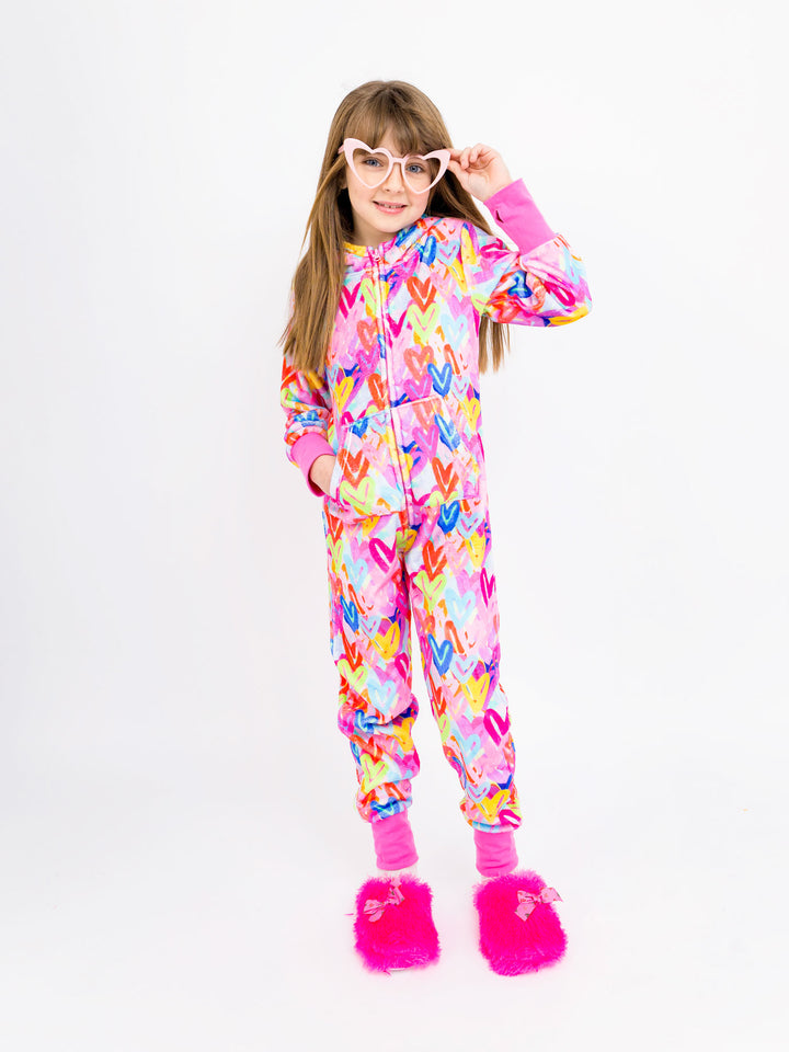 Child wearing a colorful onesie with heart patterns on a white background