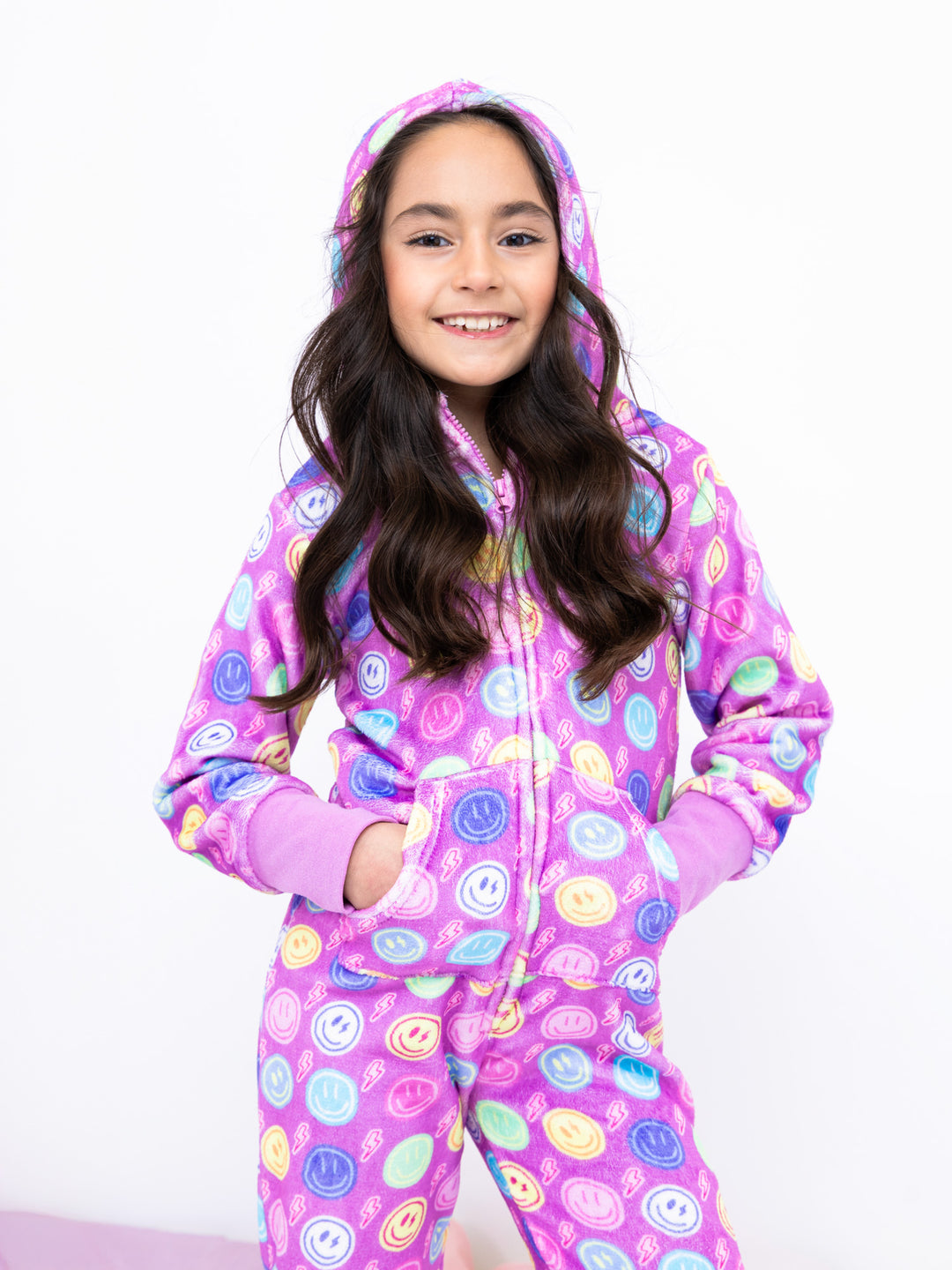 Child wearing a colorful onesie with a smiley face pattern on a white background
