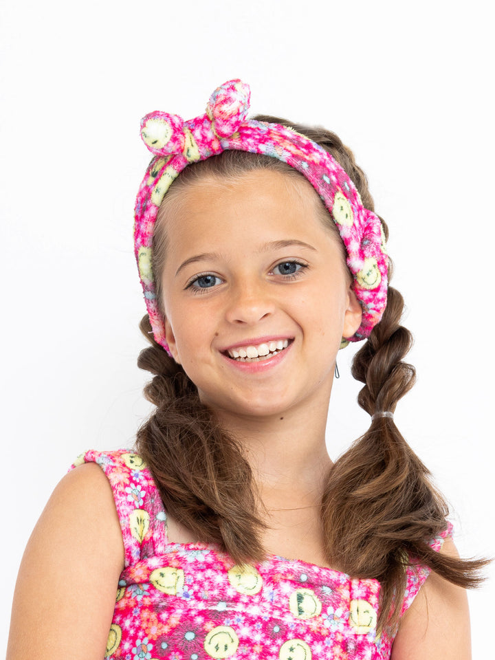 girls pink plush headband with bow in a floral smiley face print