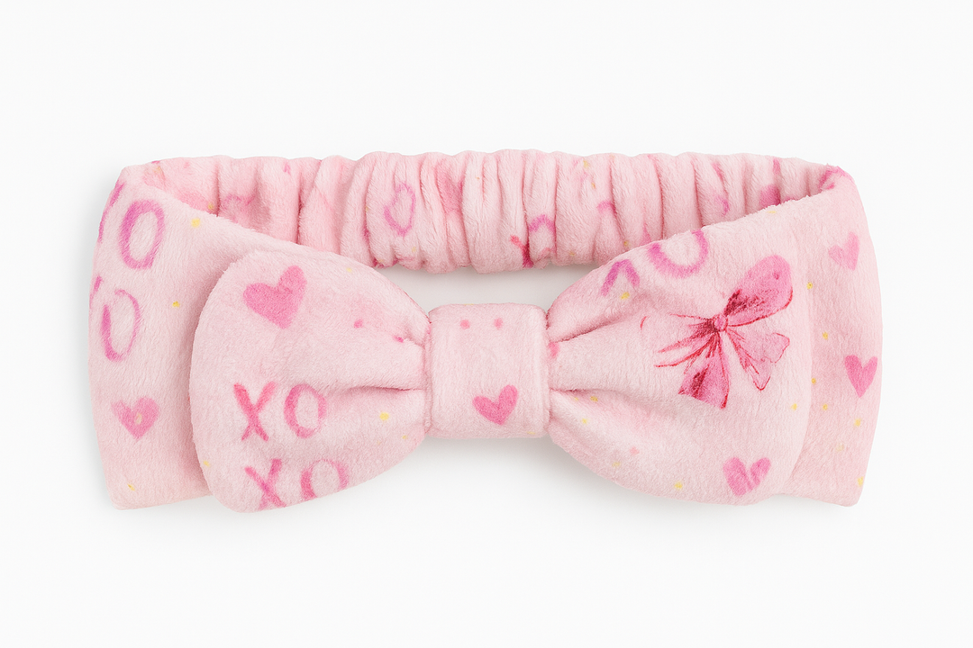 Pink headband with bow and heart designs on a white background