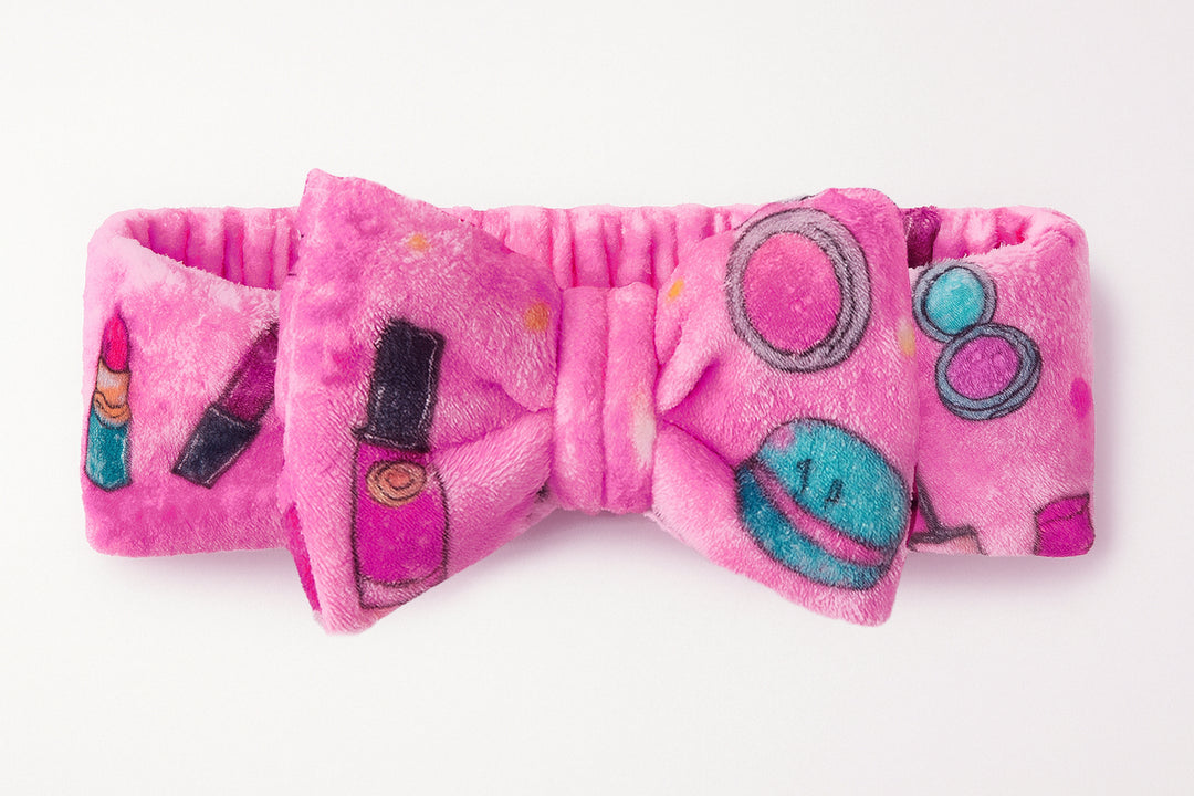 Pink plush bow with makeup and cartoon character designs on a white background