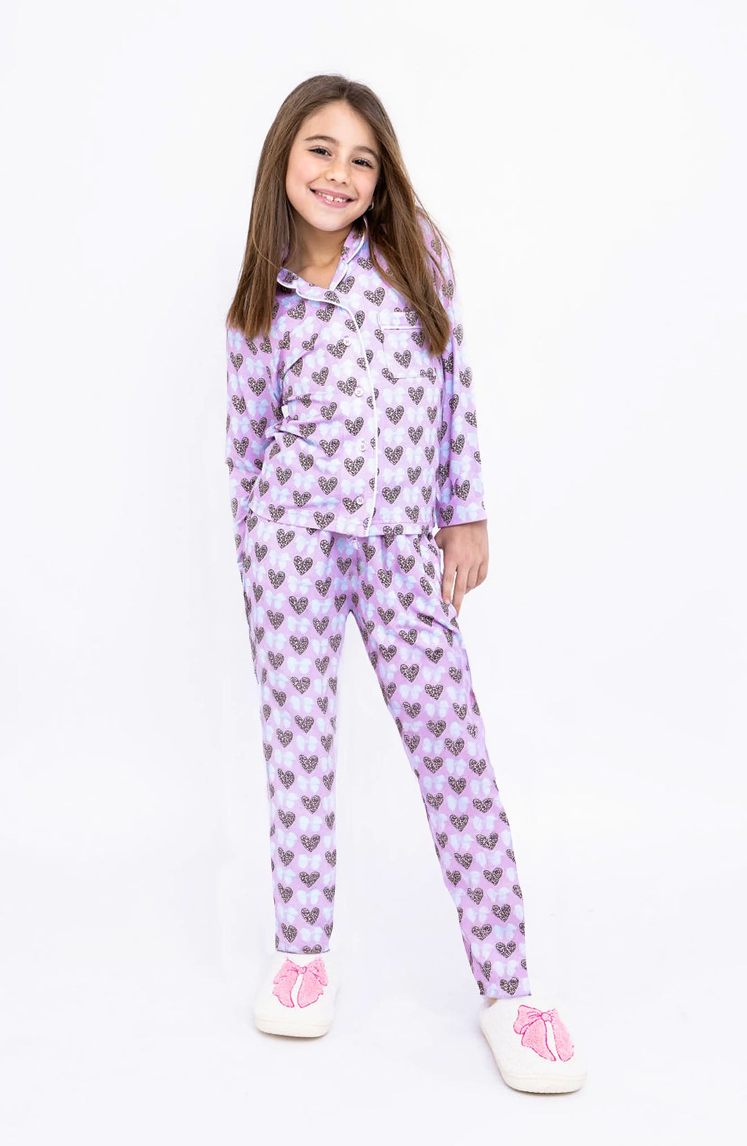 Young girl wearing a purple heart printed pattern pajama set on a white background